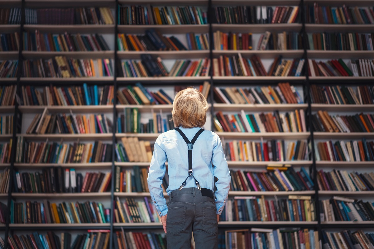 Kleiner Junge vor einem großen Bücherregal